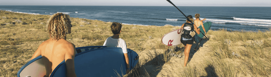 Teilnehmer gehen über die Düne im Surfcamp