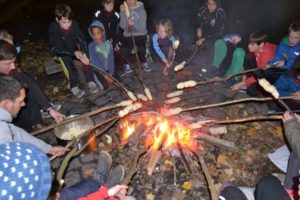 Kinder sitzen am Lagerfeuer mit Stockbrot