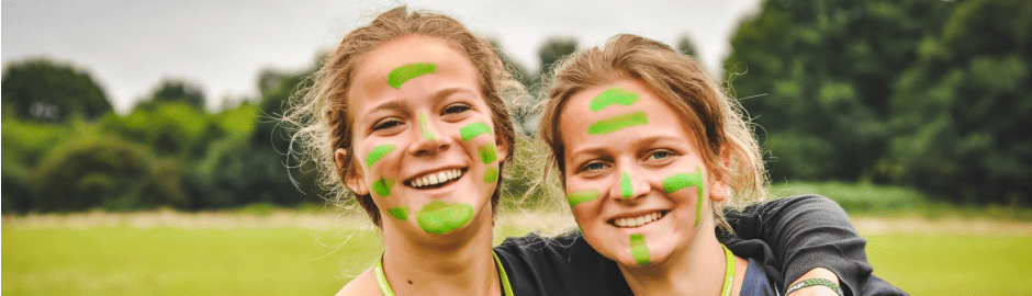 zwei lachende Mädchen mit grüner Farbe im Gesicht
