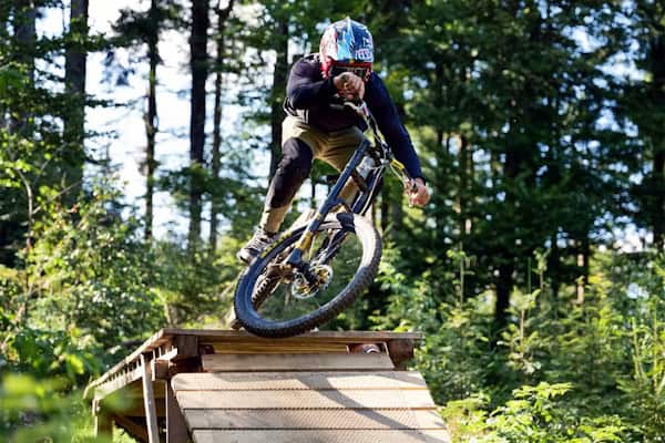 Junge fährt Parkours im Mountainbikecamp mit Englisch in Regen