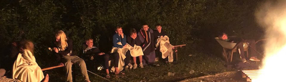 Jugendliche sitzen am Lagerfeuer
