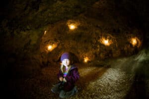 Mädchen sitzt in einer Höhle im Abenteuercamp Pottenstein