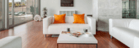 Eine Lounge mit einer weißen Couch und orangenen Kissen