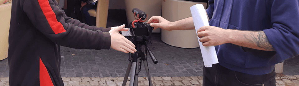 Eine Kamera steht zwischen zwei Menschen