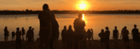 Menschen beim Sonnenuntergang am See