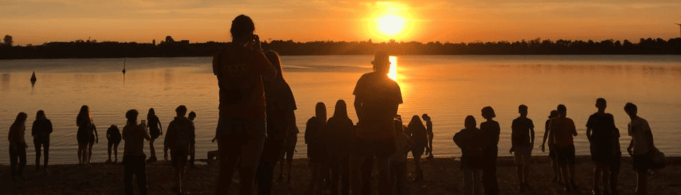 Menschen beim Sonnenuntergang am See