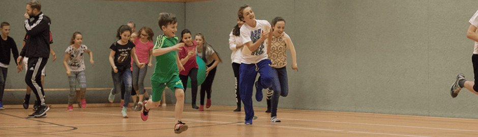 Kinder rennen durch eine Turnhalle