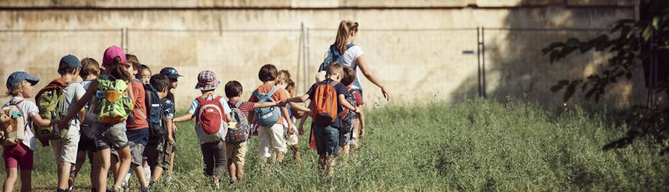 Kinder laufen der Teamerin im hohen Gras hinterher