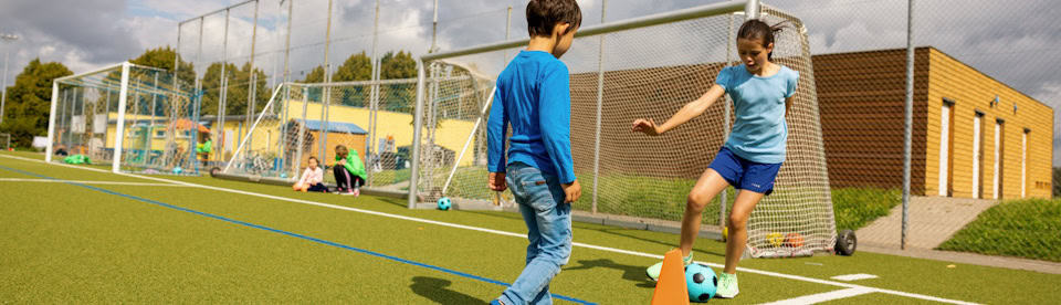 Mädchen dribbelt im Fußballcamp auf Jungen zu