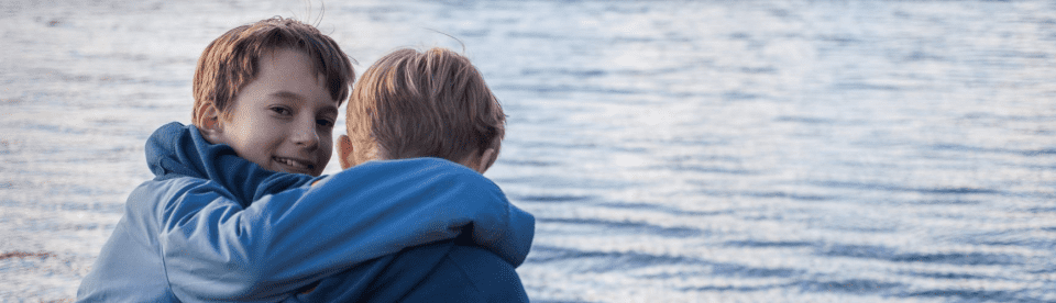 Zwei Jungen sitzen am See