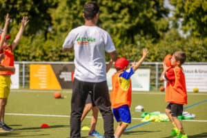 Kinder spielen im OutdoorKids Feriencamp mit einem Football