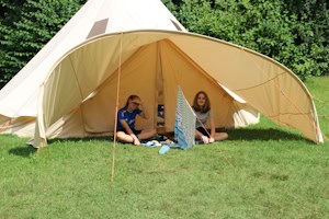 Mädchen sitzen vor Tipi im Survivalcamp