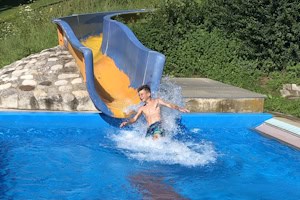 Junge auf der Wasserrutsche im Freibad