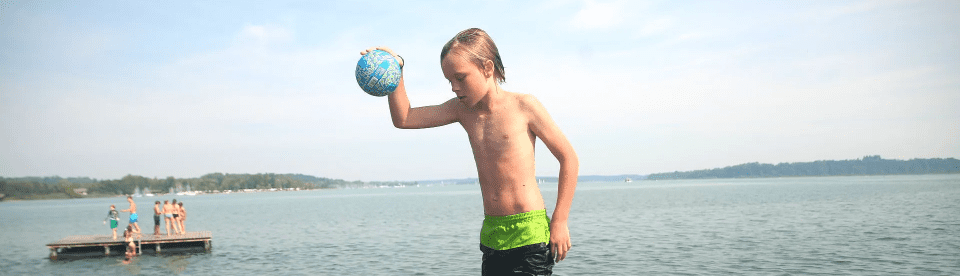 Junge mit Ball am Wasser