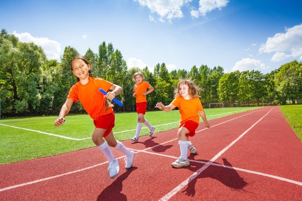 Kinder laufen auf dem Sportplatz