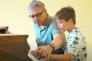 Ein Junge und ein Lehrer spielen Piano im Klavier Camp Schloss Leizen
