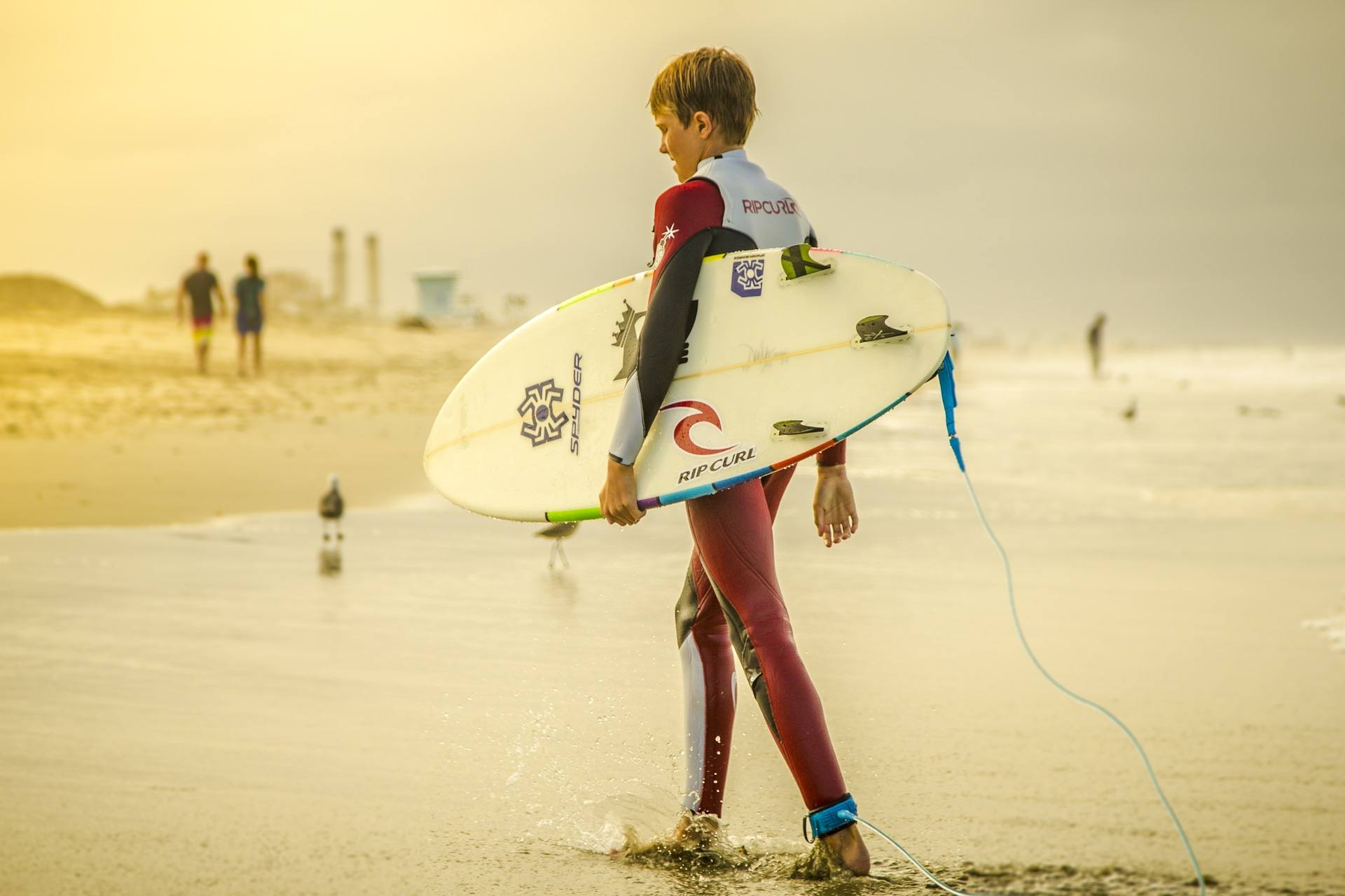 Kleiner Surfer am Strand im Feriencamp